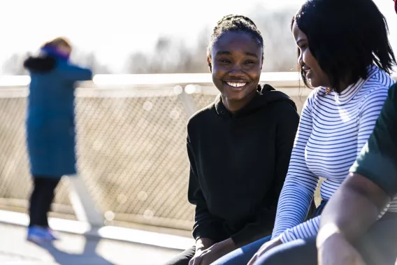 Two female students smiling and talking, while sitting on the UL Living Bridge