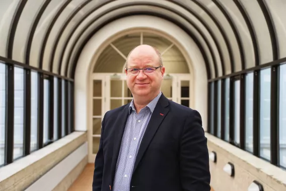 Head and shoulders colour photograph of Professor Kenneth Stanton.  He is wearing a blue shirt and navy jacket looking directly at the camera.