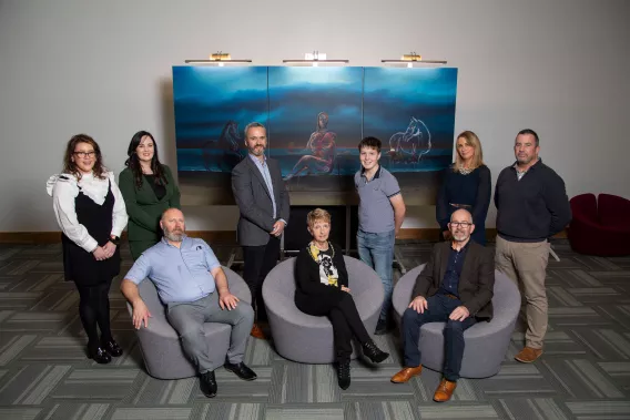 A group pictured in front of the portrait