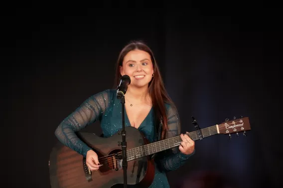 Person on stage singing and playing guitar