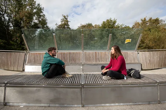 two students sitting on a bench and talking