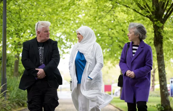 Three people walking and talking in a shaded area