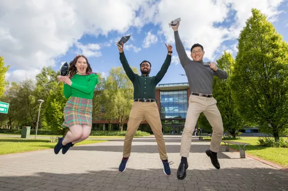 Two men and a woman jumping in the air holding aloft their prizes 