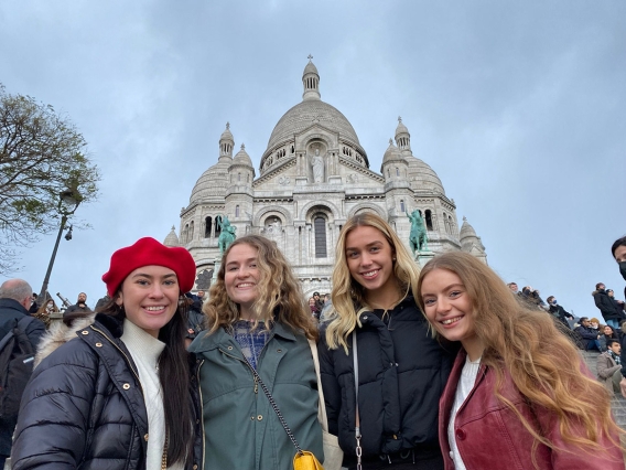Four women in winter coats standing in front of a European church