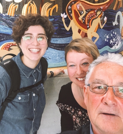 Three people taking a selfie in front of a mural