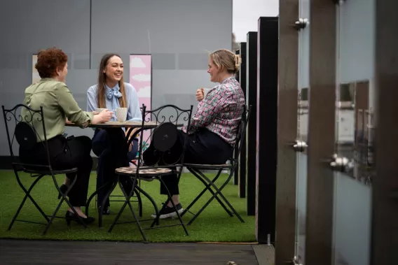 Three female colleagues seated having a cup of tea and chatting