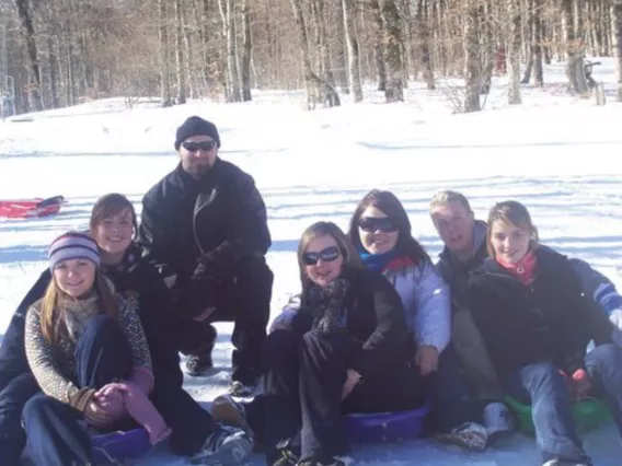 A group of seven men and women sitting in the snow.