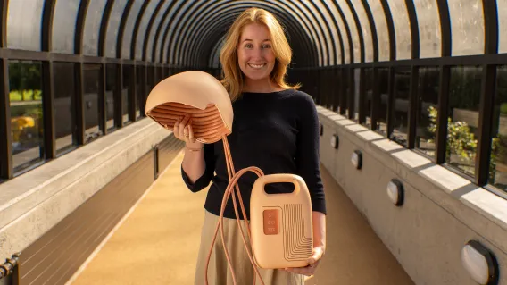 Woman standing in a tunnel holding a medical device consisting of a helmet and battery powered controller