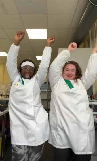 two girls in laptop coats dancing