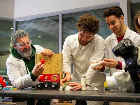 Three men in lab coats working on clay models.