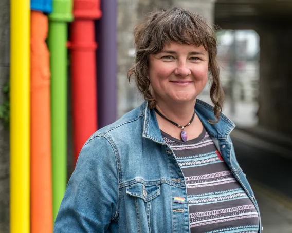 Singer in denim jacket in front of colourful background