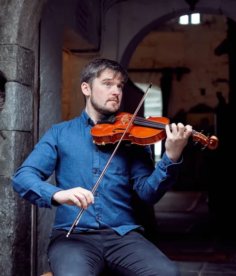 Musician sitting down playing the fiddle