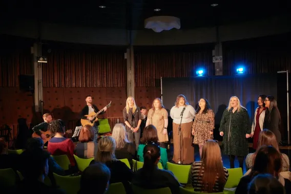 Seven singers and two guitarists performing to audience