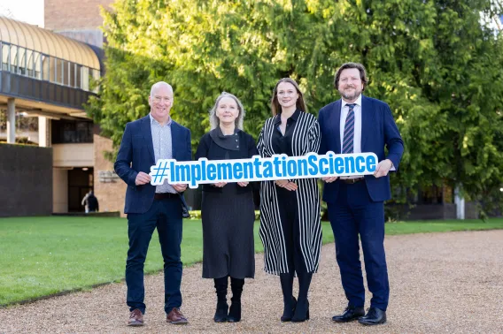 Four people pictured at UL holding a sign that says implementation science