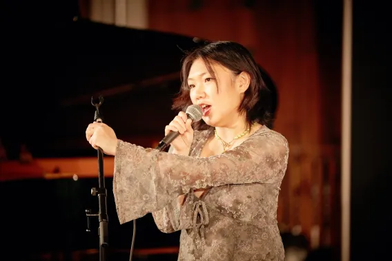 Singer performing in front of grand piano with microphone