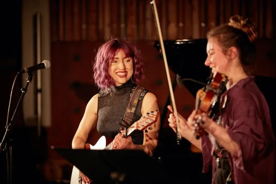 Guitarist looking at violinist and smiling