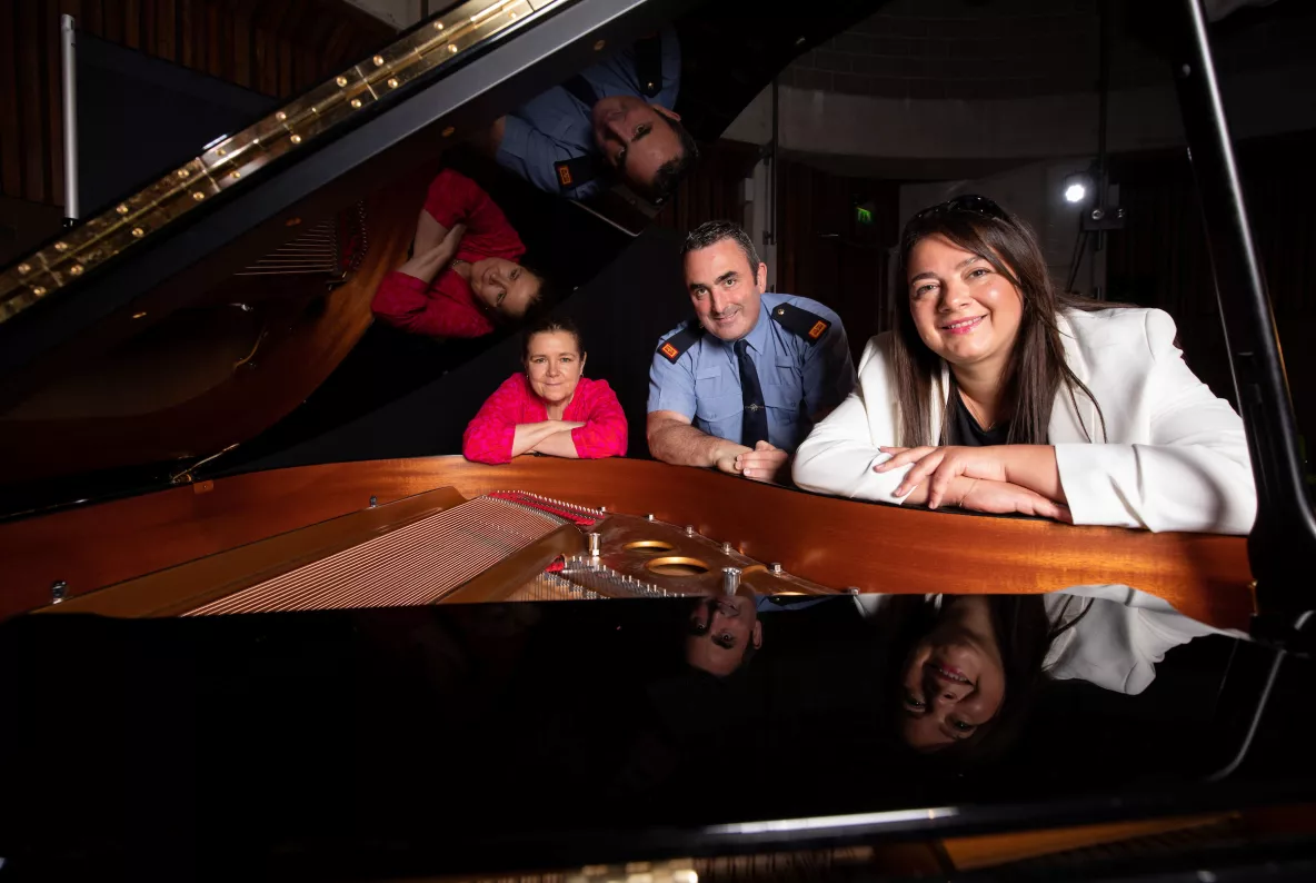 Three people at a piano in the Irish World Academy at UL