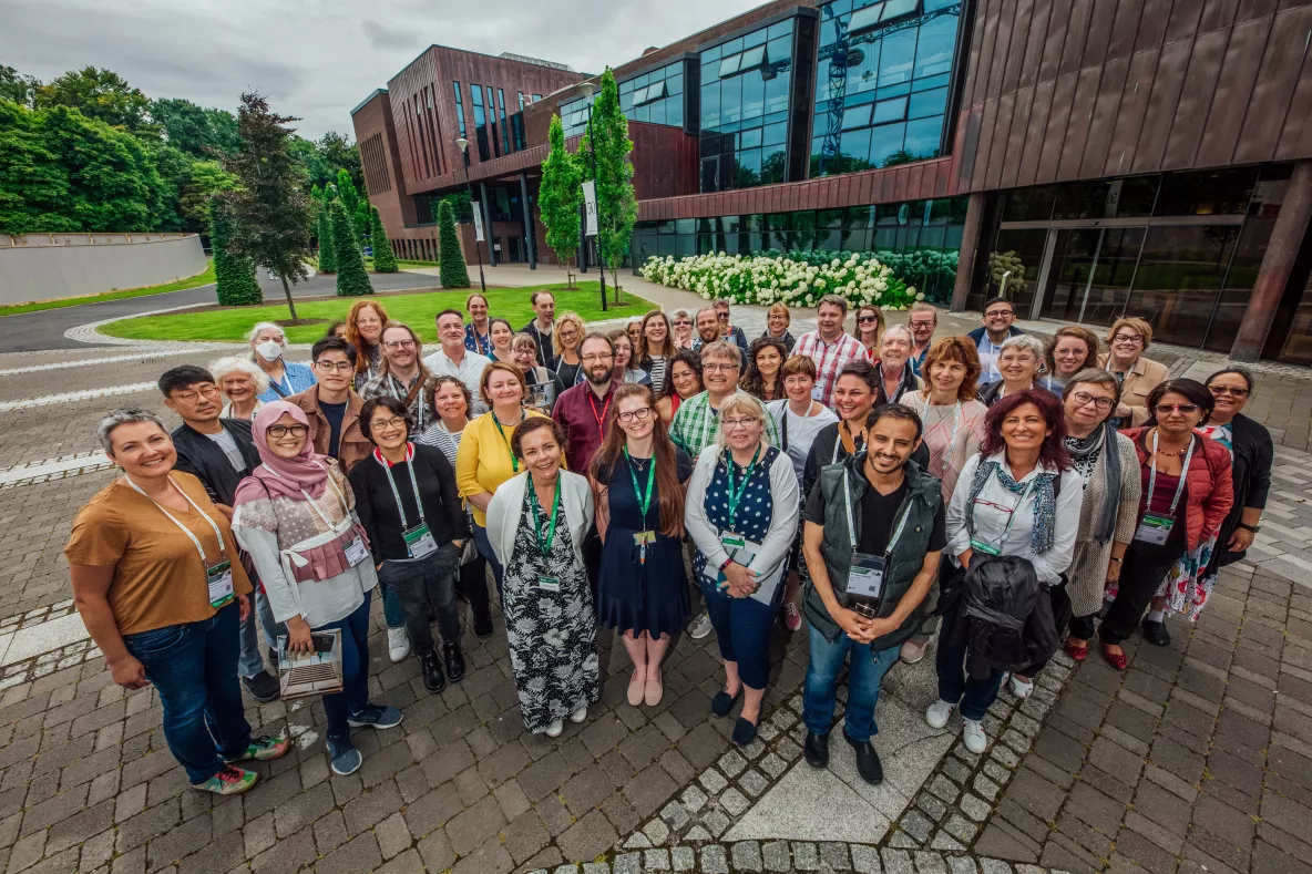 A group of circa 40 men and women with conference delegate lanyards outside the UL Glucksman Library Extension