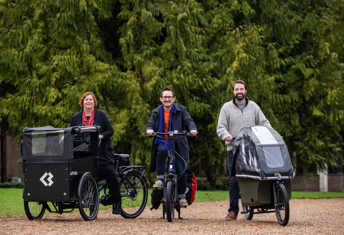 Professor Kerstin Mey, sitting on a tricycle style e-bike, Dr James Green also on a e-bike and Brian Leddin TD on an e-bike with a childrens carrier in the front. 