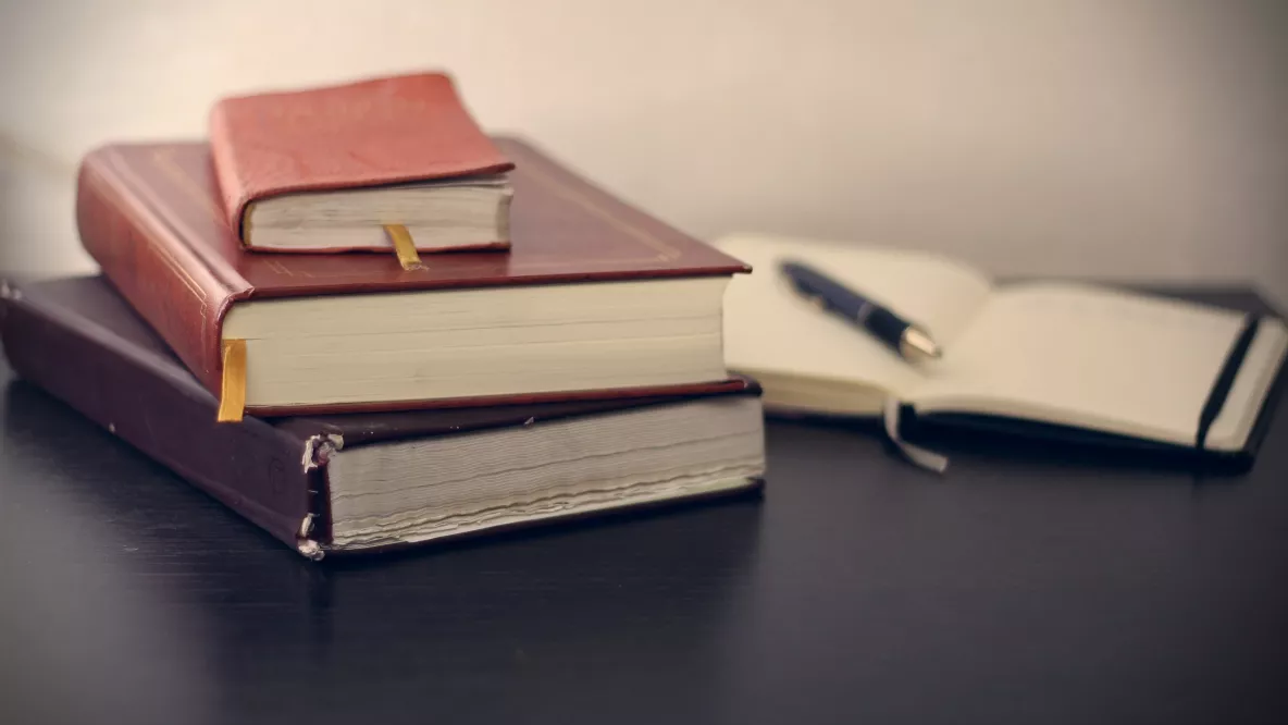 pile of three books with open notebook in background