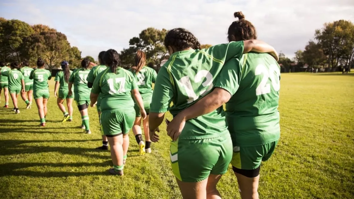 Female Rugby players walking arm in arm on a field