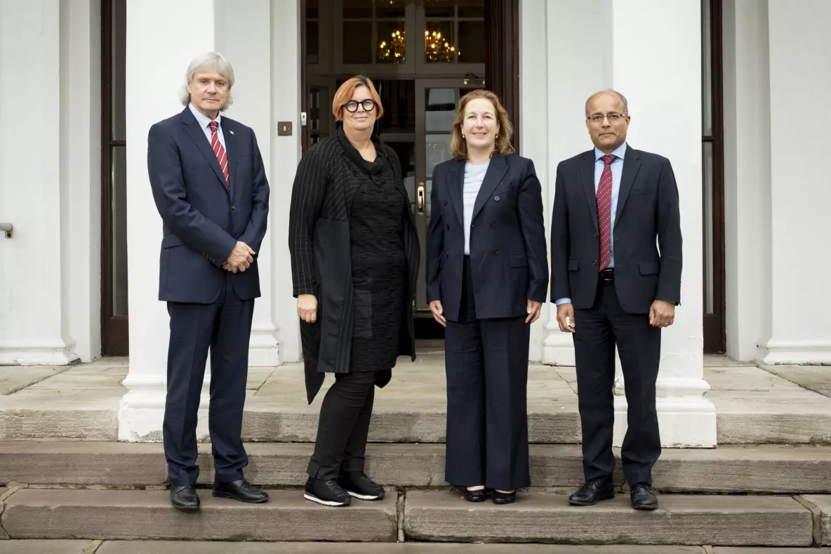 A group shot of four people on the steps of Plassey House. 