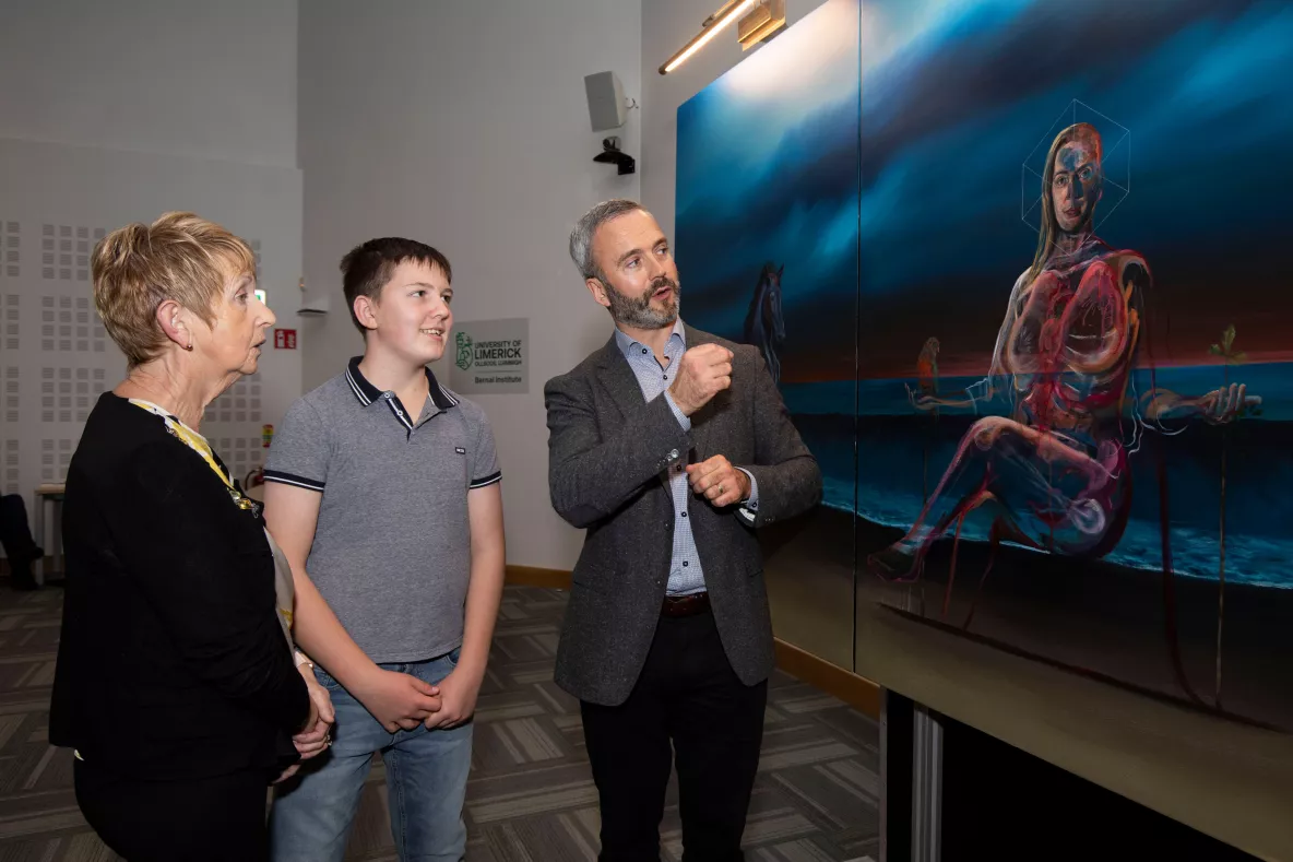 Three people looking at a large painting - they are Vicky Phelan's mother and son and friend David Brennan