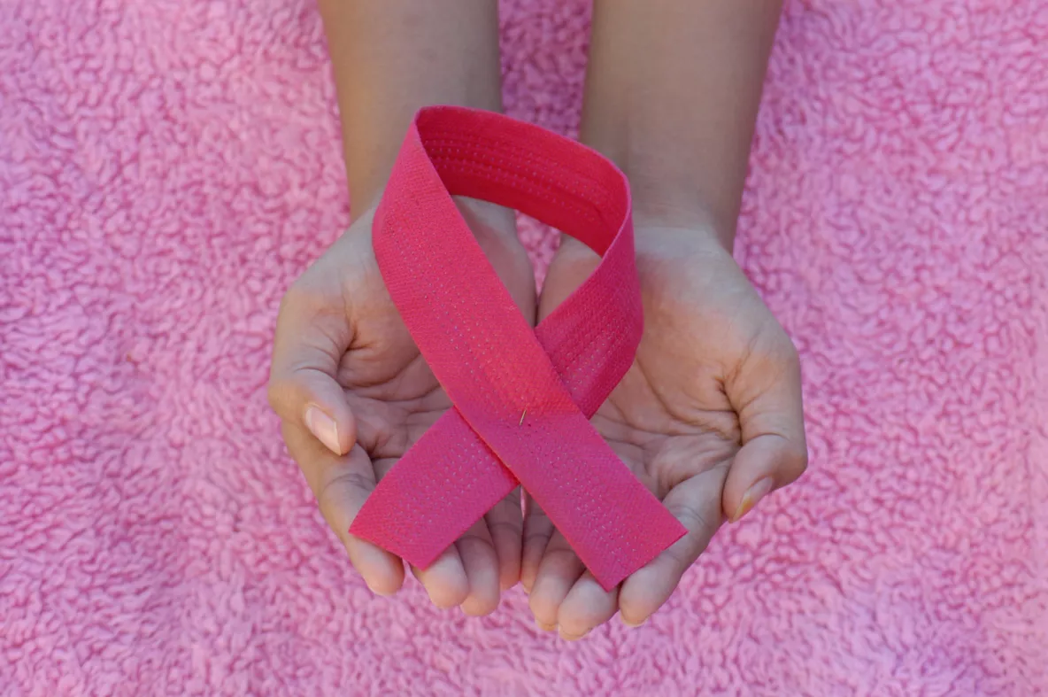 Cupped hands holding pink looped ribbon