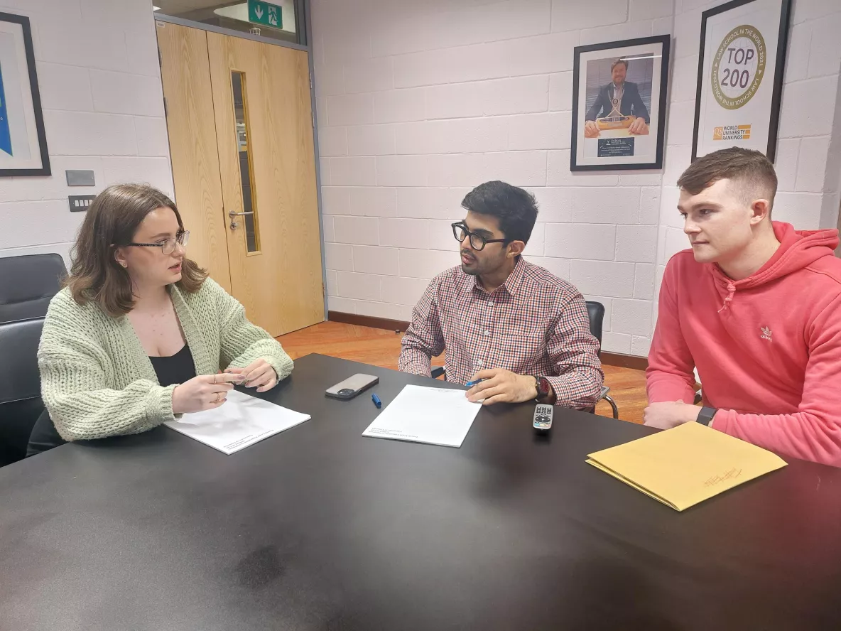 three chosen students discussing their internship in the school of law boardroom