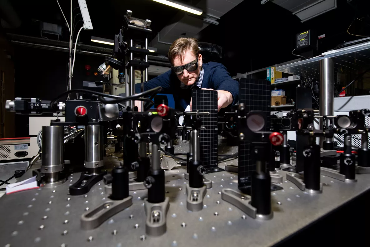 A researcher wearing glasses operating with machinery in a lab