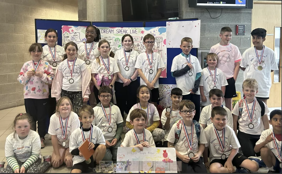 Group of children wearing which tshirt and medals in a classroom