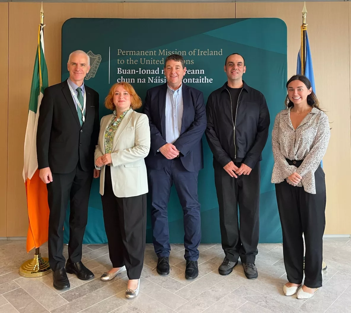 3 men and two females standing facing the camera with the Irish flag to the left hand side of them