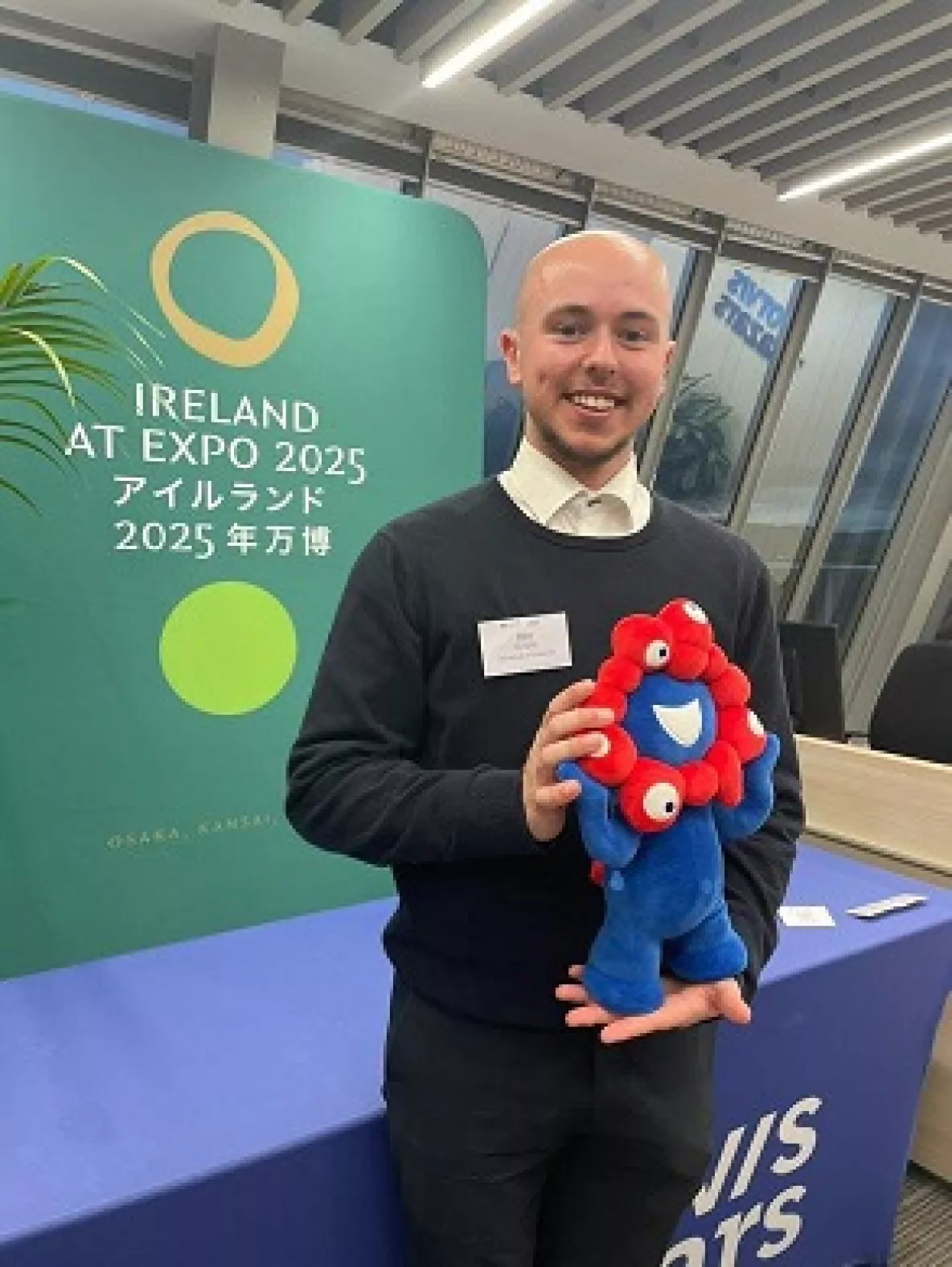 Ben Murphy smiling at the seminar holding the mascot of the EXPO, whose name is Myaku Myaku.