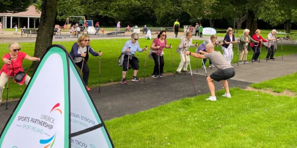 Group of older adults with poles doing exercise in a park