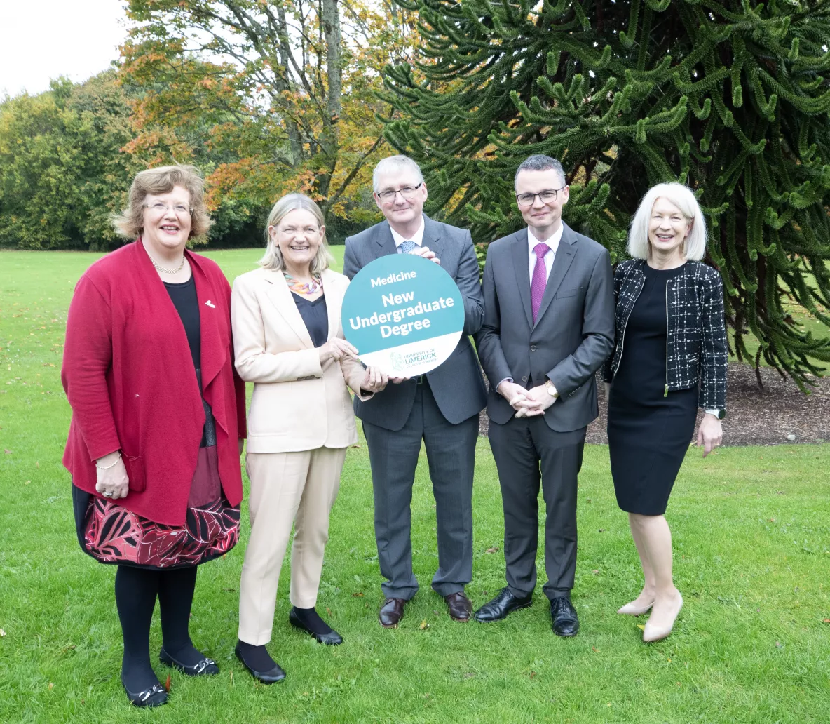 A group of five people at UL holding a sign that says new undergraduate degree. They are outside on the lawn of Plassey House at UL