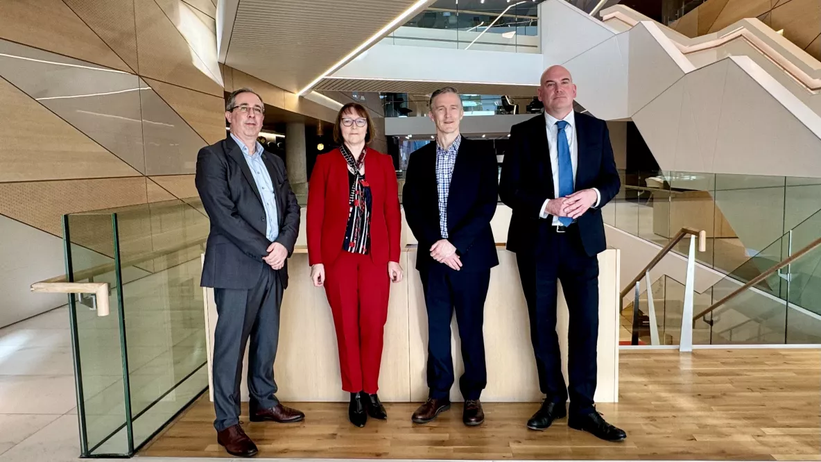 A picture of four people indoors - they are three men and one woman