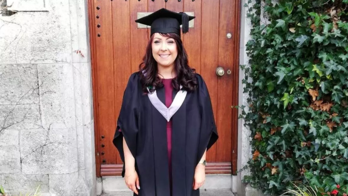 Picture of a woman in graduation robes smiling for photo