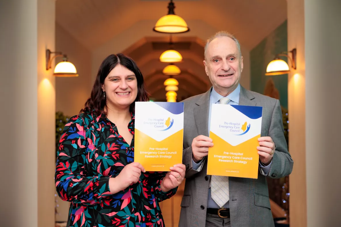 A picture of two people holding up documents - they are Dr Niamh Cummins and Pat Fleming