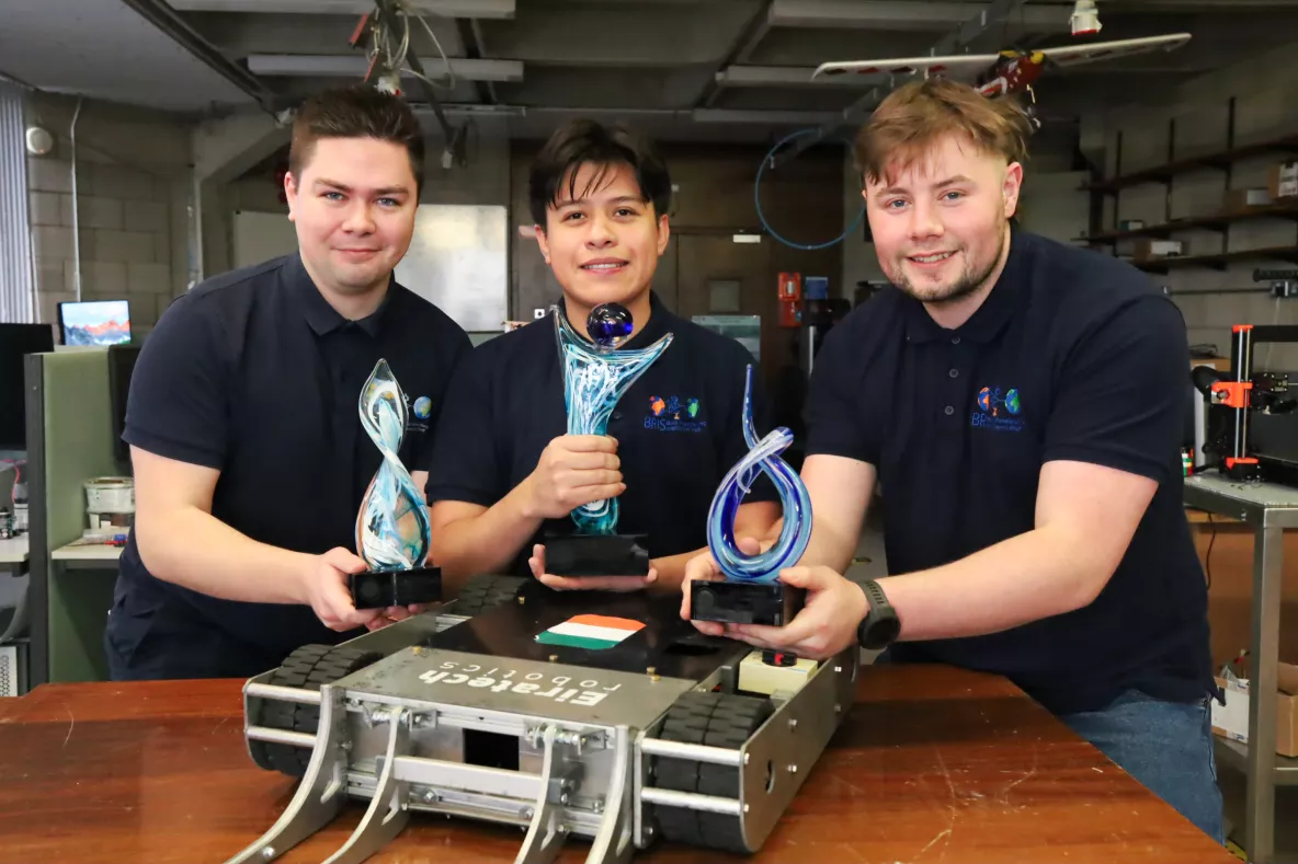 Three students pictured at UL with a robot they designed