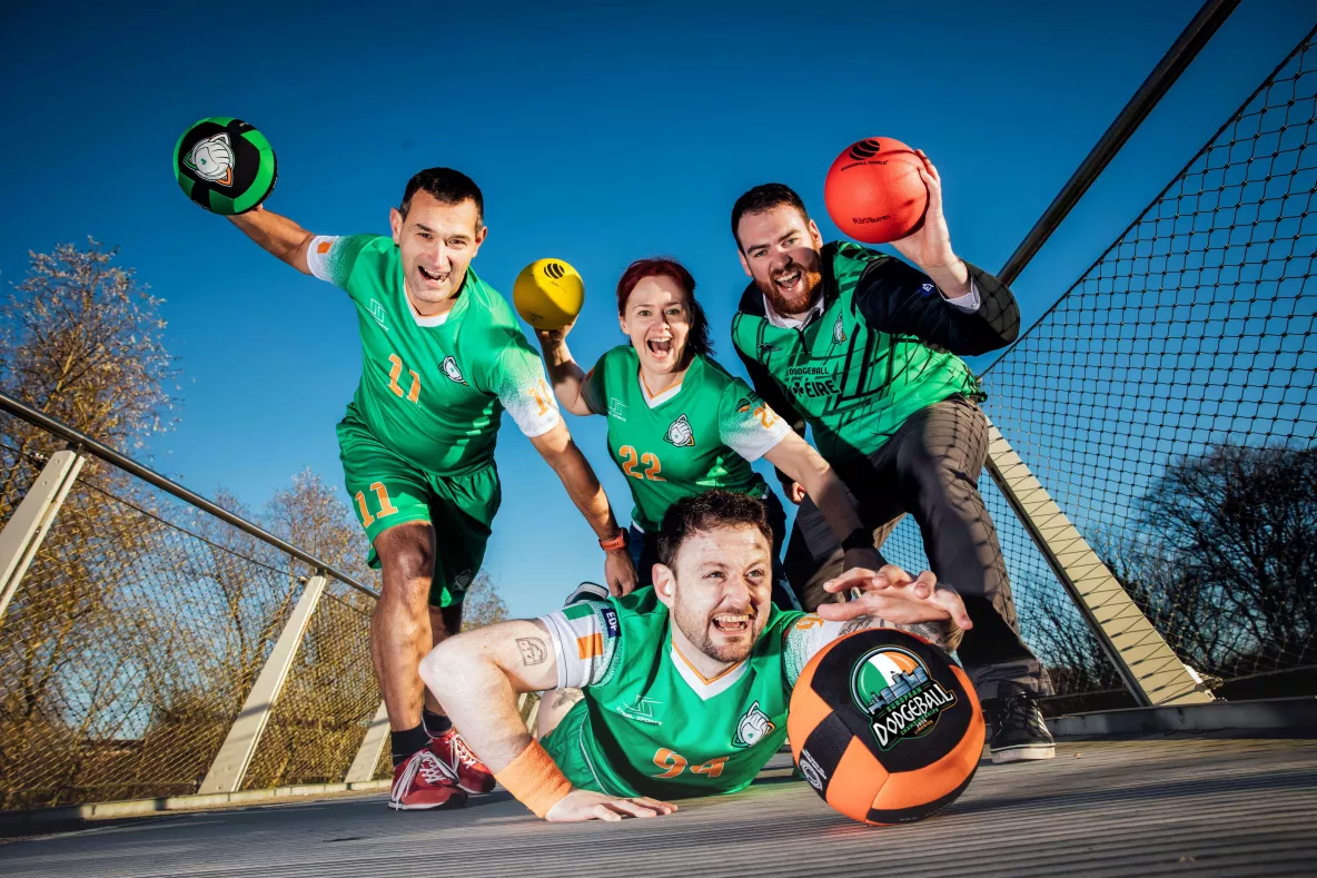 Four dodgeball athletes wearing Irish dodgeball team jerseys pose for a photo on the living bridge in University of Limerick