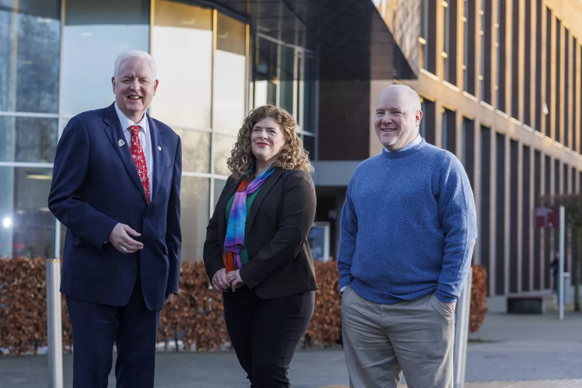 woman and two men standing in front of building