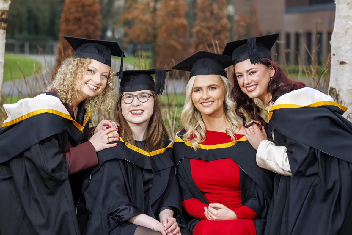 A picture of four students in graduation robes on the UL campus