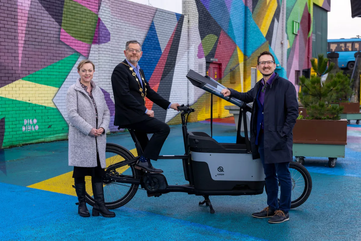 A picture of three people standing beside a large e-bike - they are Irene Ward, Mayor John Moran and James Green