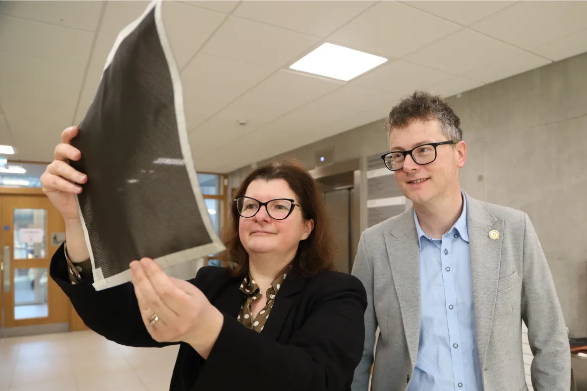 A picture of two UL academics looking at a sheet of carbon fibre