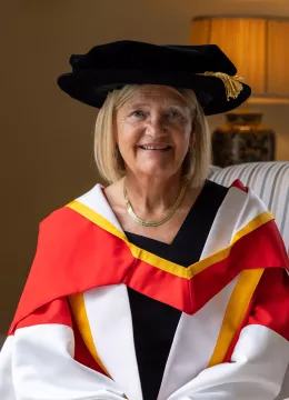 A picture of Professor Brigid Laffan in her robes, sitting in a chair