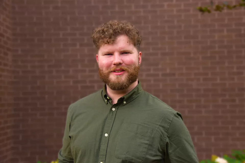 A an with a beard and curly hair smiling