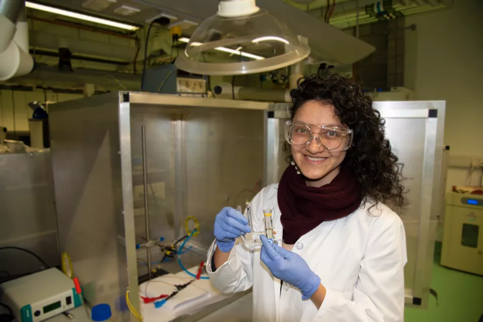 A woman with brown curly hair holding a medical device in a lab