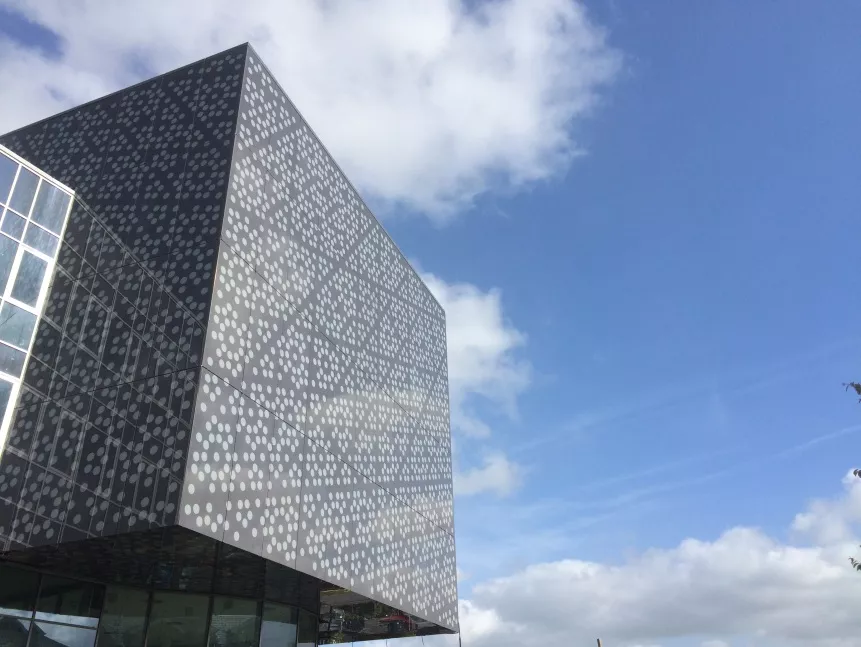 Square grey building with blue sky and clouds