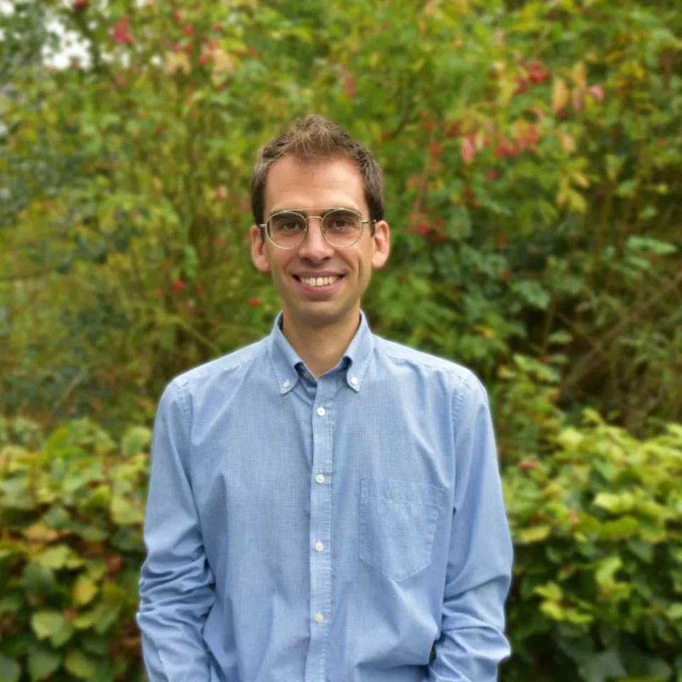 A man with a blue shirt and glasses smiling