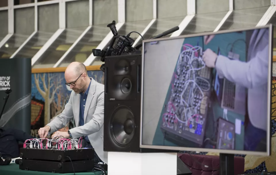 Man playing electronic music using a computer board, on right is close up image of the board